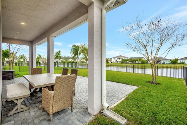 view of patio with outdoor dining area, a water view, and a fenced backyard