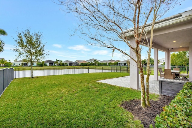 view of yard featuring a patio area, a water view, a fenced backyard, and a residential view