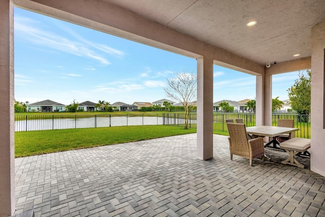 view of patio featuring outdoor dining area, a water view, a fenced backyard, and a residential view