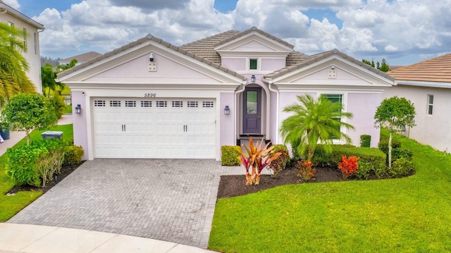 view of front of home with a garage, a tile roof, decorative driveway, and a front yard