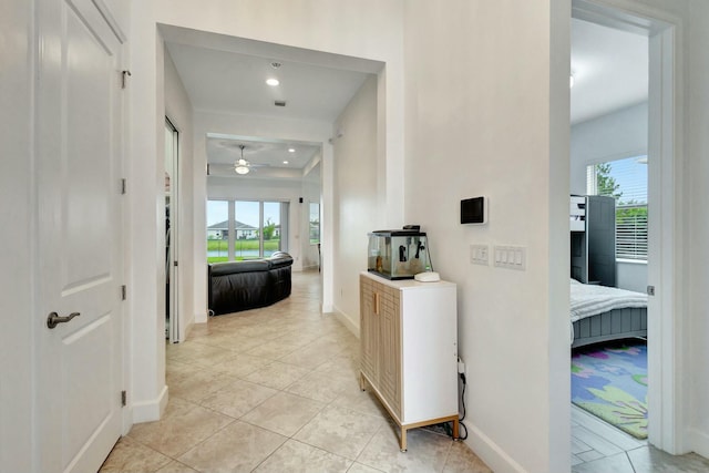 corridor featuring light tile patterned floors, baseboards, and recessed lighting