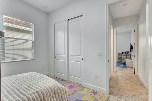 bedroom with baseboards, a closet, and light tile patterned flooring