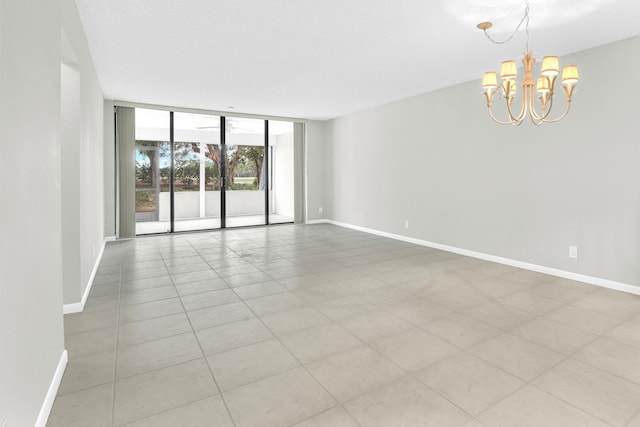 empty room with a wall of windows, baseboards, and a chandelier