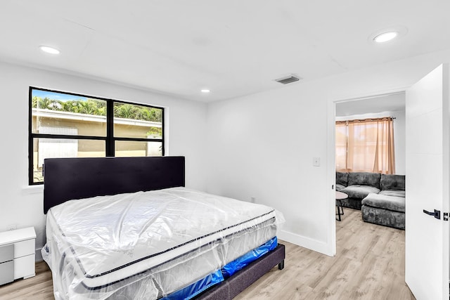 bedroom with light wood-type flooring, baseboards, and recessed lighting