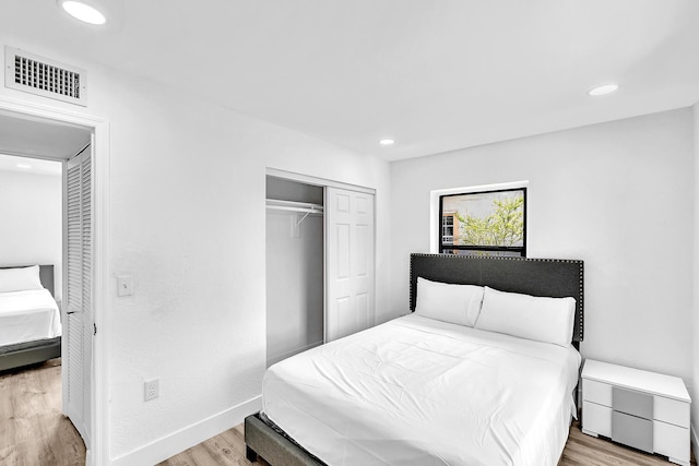 bedroom featuring recessed lighting, wood finished floors, visible vents, baseboards, and a closet