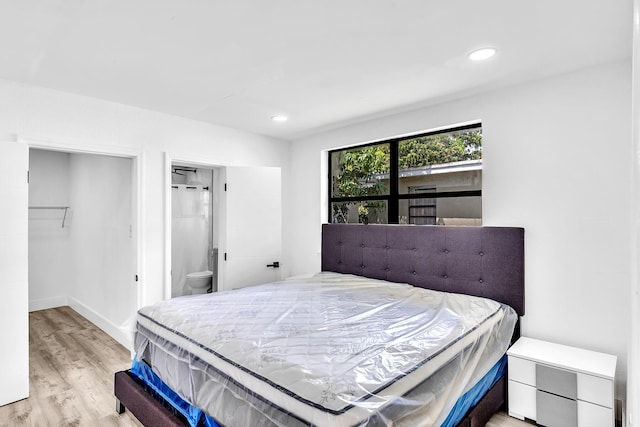 bedroom featuring baseboards, light wood-type flooring, ensuite bathroom, and recessed lighting