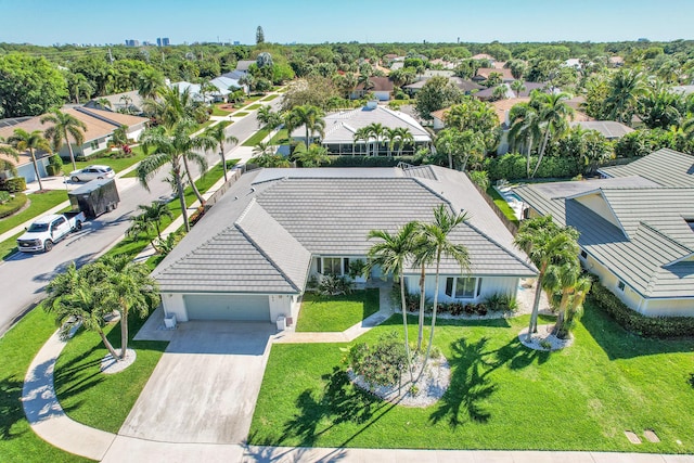 view of front of property featuring a garage, a tile roof, driveway, and a front lawn