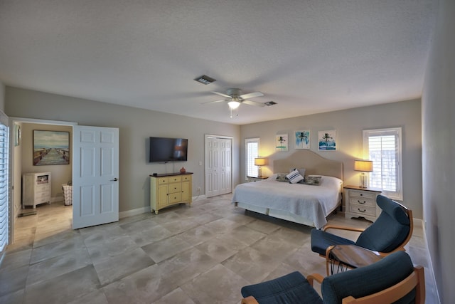 bedroom featuring a ceiling fan, visible vents, baseboards, a closet, and a textured ceiling