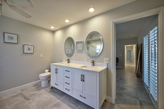 bathroom with a sink, baseboards, double vanity, and recessed lighting