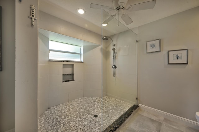 bathroom featuring baseboards, toilet, ceiling fan, and a walk in shower