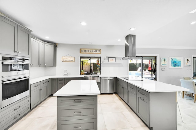 kitchen with gray cabinetry, light countertops, a peninsula, island exhaust hood, and stainless steel appliances