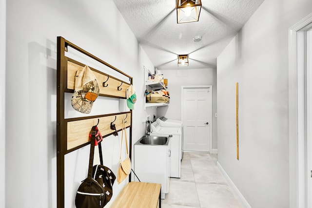 clothes washing area with light tile patterned floors, baseboards, laundry area, a textured ceiling, and independent washer and dryer