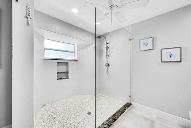 bathroom featuring baseboards, toilet, ceiling fan, and a tile shower