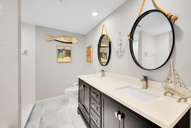 bathroom featuring double vanity, toilet, baseboards, and a sink