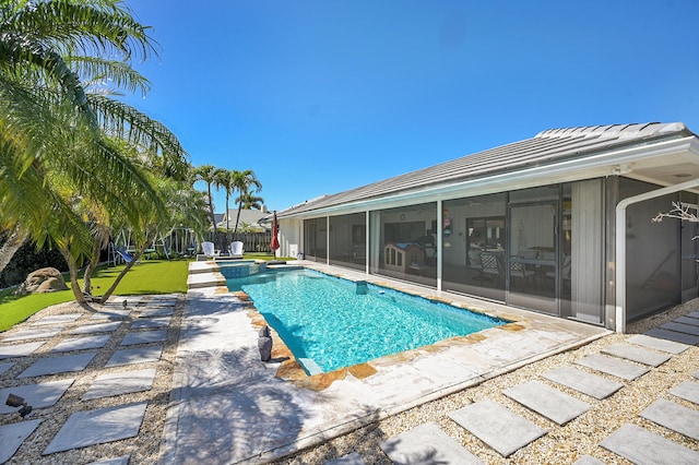 view of swimming pool featuring a patio, a fenced backyard, a pool with connected hot tub, a sunroom, and a lawn