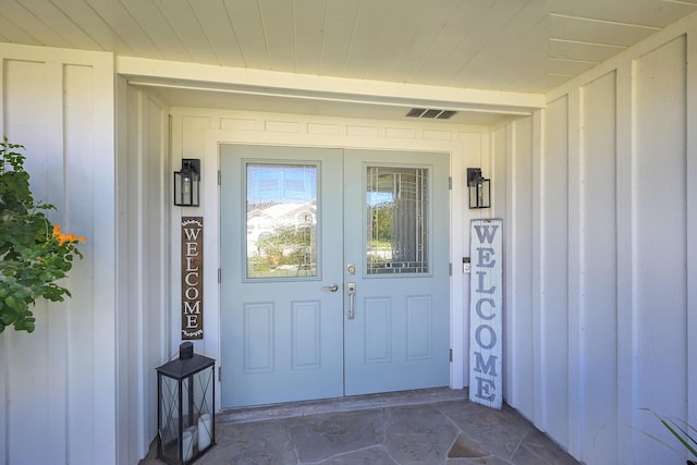 view of exterior entry with visible vents and board and batten siding