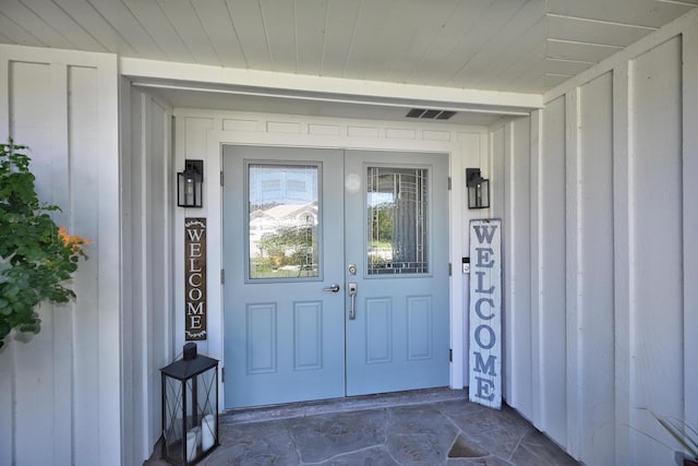 view of exterior entry featuring board and batten siding and visible vents