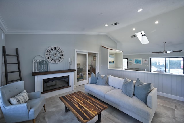 living room with visible vents, lofted ceiling with skylight, a glass covered fireplace, and crown molding