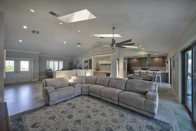 living room featuring visible vents, vaulted ceiling with skylight, and crown molding