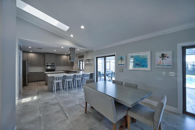 dining space featuring vaulted ceiling with skylight, recessed lighting, baseboards, and ornamental molding