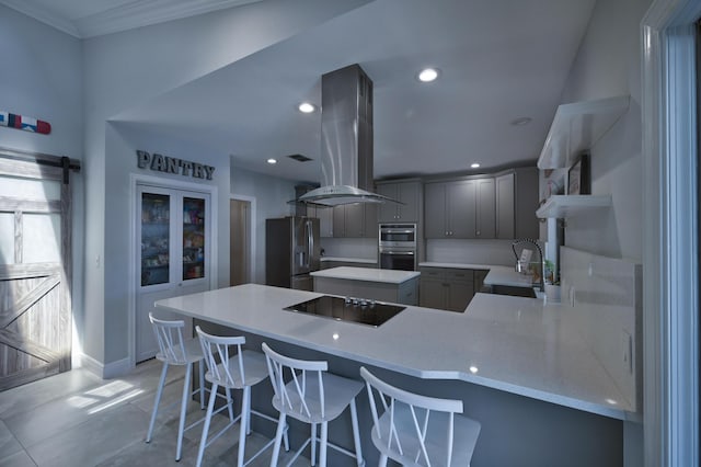 kitchen featuring a peninsula, open shelves, island exhaust hood, gray cabinetry, and appliances with stainless steel finishes