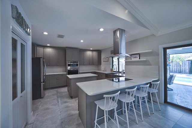 kitchen with a peninsula, island exhaust hood, freestanding refrigerator, a sink, and black electric cooktop