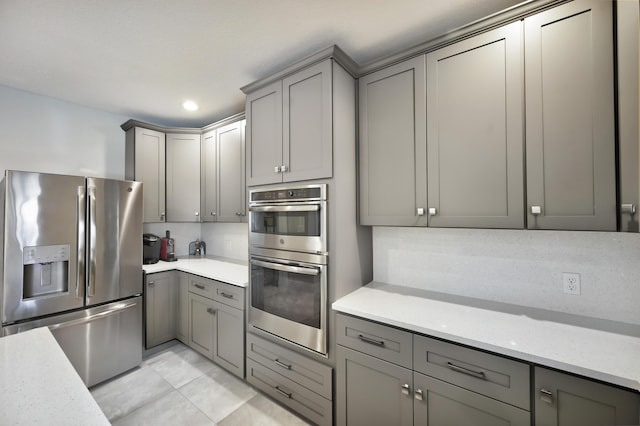 kitchen with gray cabinetry, decorative backsplash, recessed lighting, appliances with stainless steel finishes, and light tile patterned flooring