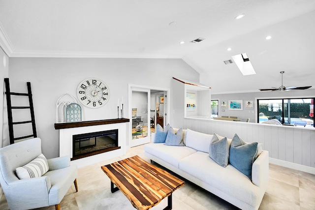 living area featuring a glass covered fireplace, vaulted ceiling with skylight, visible vents, and ornamental molding