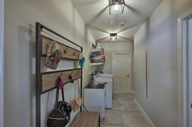 laundry area featuring washer and dryer, baseboards, a textured ceiling, and laundry area