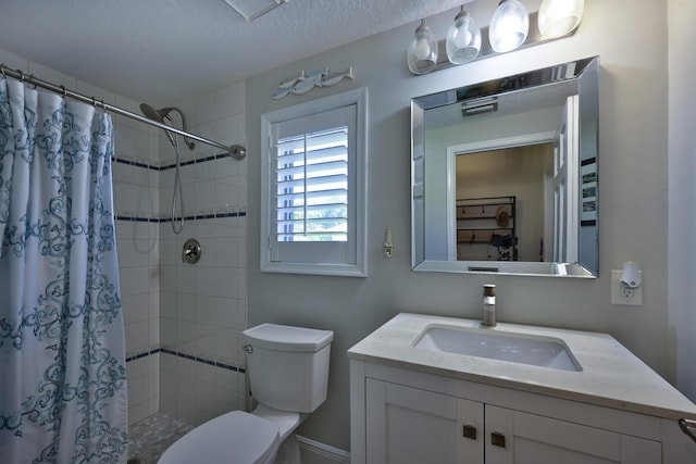 bathroom with a tile shower, a textured ceiling, toilet, and vanity