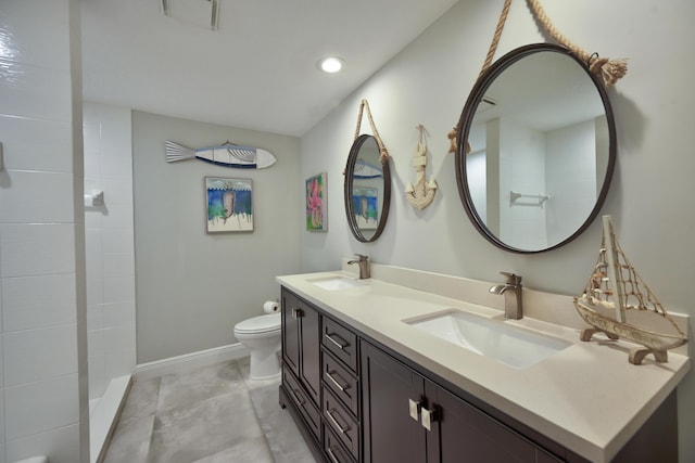 full bath with a sink, tiled shower, toilet, and double vanity