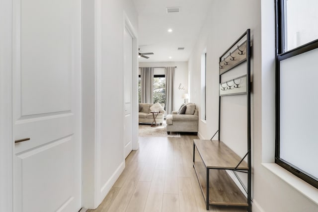 hallway featuring light wood-type flooring, baseboards, visible vents, and recessed lighting