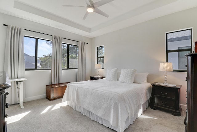 bedroom with baseboards, ceiling fan, a tray ceiling, and light colored carpet