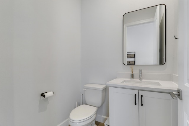 half bathroom with vanity, toilet, and baseboards