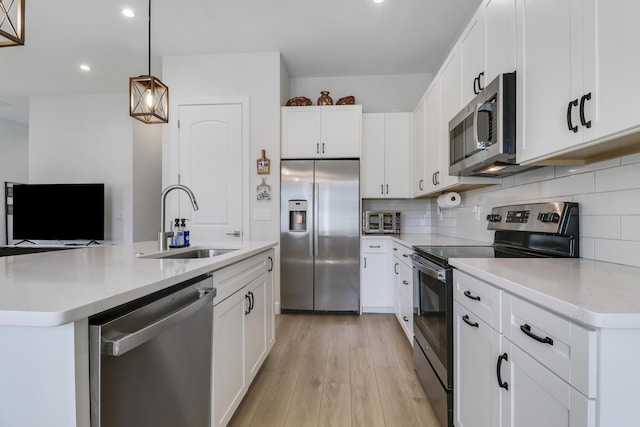 kitchen with a kitchen island with sink, stainless steel appliances, a sink, light wood finished floors, and tasteful backsplash