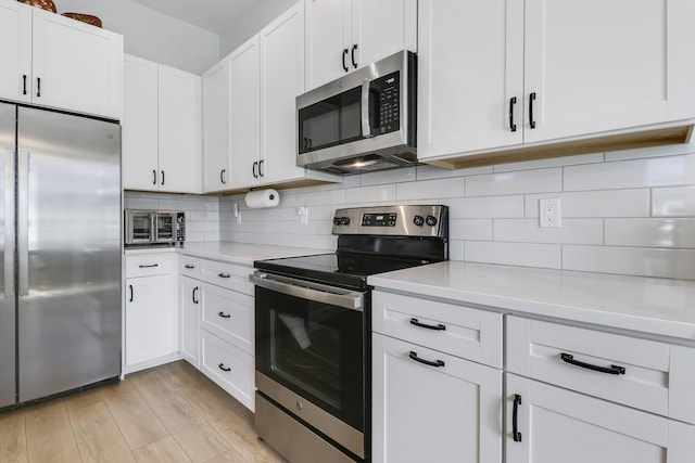 kitchen featuring stainless steel appliances, white cabinets, light countertops, light wood-type flooring, and decorative backsplash