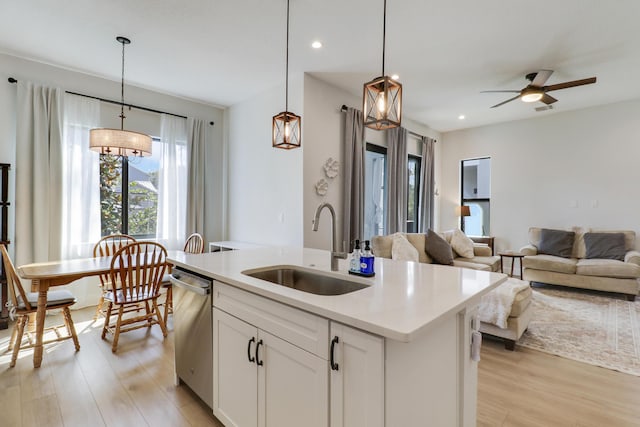 kitchen with a sink, light wood-style floors, open floor plan, light countertops, and dishwasher