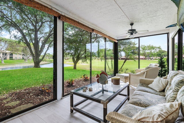 sunroom / solarium featuring a ceiling fan and a water view