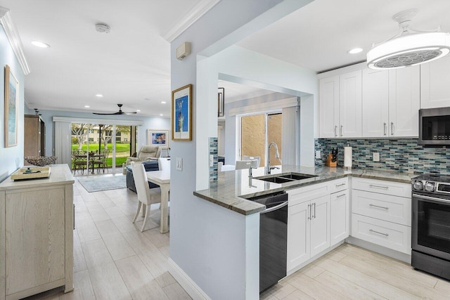 kitchen featuring dark stone countertops, ornamental molding, decorative backsplash, a sink, and appliances with stainless steel finishes