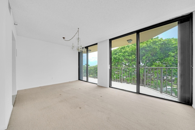 carpeted spare room with baseboards, expansive windows, and a chandelier