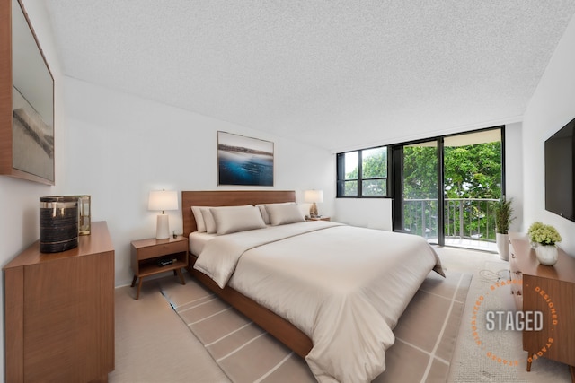 carpeted bedroom featuring a textured ceiling and a wall of windows