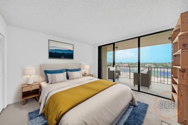 bedroom featuring a textured ceiling, a wall of windows, light colored carpet, and access to exterior