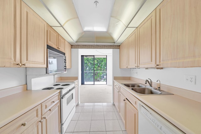 kitchen with white appliances, a raised ceiling, light countertops, light brown cabinets, and a sink