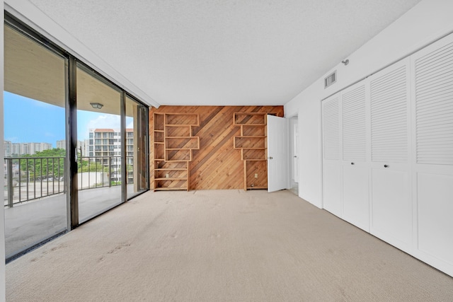 interior space featuring wooden walls, a city view, visible vents, access to exterior, and carpet