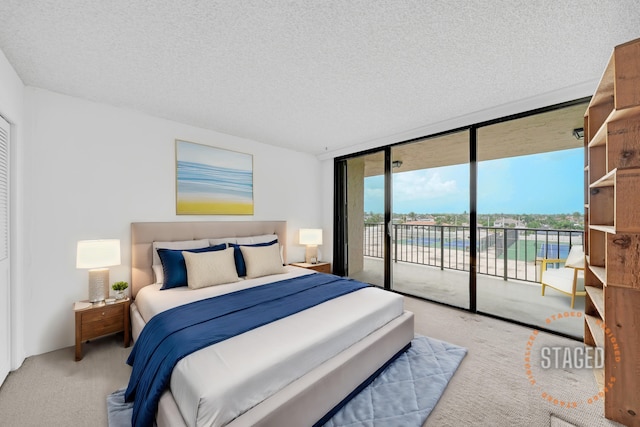 bedroom with access to exterior, floor to ceiling windows, a textured ceiling, and light colored carpet