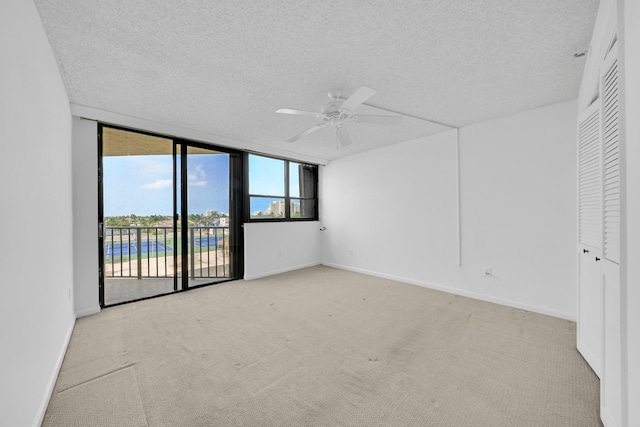 unfurnished room featuring a textured ceiling, carpet floors, a ceiling fan, baseboards, and floor to ceiling windows