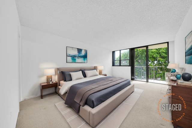 bedroom featuring a wall of windows, light colored carpet, and a textured ceiling