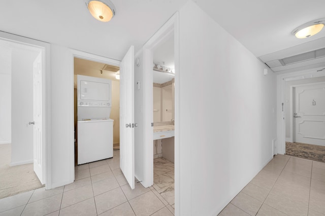 hallway featuring stacked washer and clothes dryer and light tile patterned floors