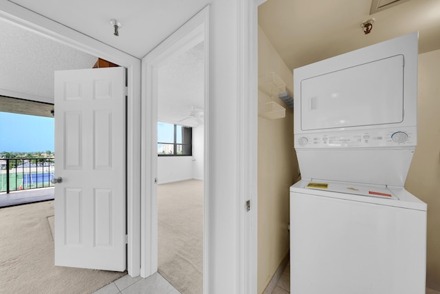 laundry room with stacked washer / dryer, laundry area, light carpet, and light tile patterned floors