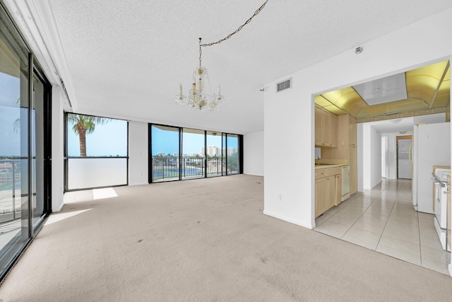 unfurnished living room with light carpet, an inviting chandelier, expansive windows, and visible vents